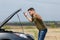 Photo of frustrated man next to broken car with open hood