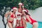 Photo of funky charming santa claus snow maidens wear red bikinis enjoying pool water celebrating new year outdoors