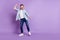 Photo of funky charming young man wear jeans shirt dancing smiling empty space isolated violet color background