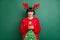 Photo of funky cute young woman dressed red pullover antlers smiling typing modern device isolated green color