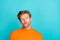 Photo of funky doubtful young man wear orange pullover looking empty space isolated teal color background