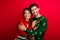 Photo of funky dreamy married couple wear ornament sweaters embracing isolated red color background