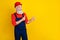 Photo of funky positive senior guy dressed uniform overall red hardhat looking pointing empty space isolated yellow