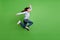 Photo of funky pretty schoolgirl wear blue turtleneck jumping high running fast empty space smiling isolated green color