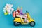 Photo of funky sweet husband wife driving motorcycle dressed hats holding presents balloons isolated blue color