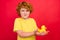 Photo of funny candid ginger little boy hold rubber duck toy wear yellow t-shirt isolated red color background