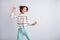 Photo of funny charming young woman dressed striped pullover dancing rising fists empty space isolated grey color
