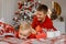 Photo of funny cheerful father tickle his laughing little son wearing red sweaters in decorated xmas room