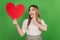 Photo of funny excited romantic lady hold red heart card look side wear casual clothes