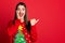 Photo of funny excited woman dressed ugly pullover arm cheek pointing thumb up empty space smiling isolated red color