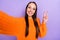 Photo of funny influencer lady make selfie show v-sign wear orange sweater isolated violet color background