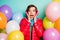 Photo of funny lady hands on cheeks surrounded many colorful air balloons surprise party wear casual red coat scarf