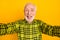 Photo of funny old man pensioner happy positive smile grimace fooling tongue-out make selfie isolated over yellow color