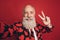 Photo of funny old man take selfie show v-sign toothy smile wear heart print tuxedo isolated red background