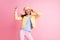 Photo of funny optimistic lady listen music dancing wear cap headphones yellow jacket blue shirt pants isolated on pink
