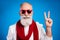 Photo of funny pretty mature man dressed white pullover red showing v-sign smiling glasses isolated blue color