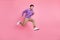 Photo of funny purposeful young man dressed purple pullover jumping hurrying isolated pink color background