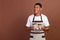Photo of funny young brunet waiter guy hold beverages look advert wear white t-shirt apron isolated on brown color