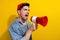 Photo of furious angry man dressed jeans shirt screaming loud speaker empty space isolated yellow color background