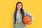 photo of glad teen basketball girl with ball. teen basketball girl isolated on yellow.