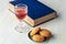 A photo of a glass of sweet wine with cookies, a book