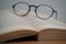 Photo of glasses and an old yellowed book on a wooden table