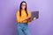 Photo of good mood adorable girl straight hairdo dressed yellow shirt hold laptop typing email isolated on purple color