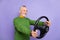 Photo of good mood retired man wear green sweater riding vehicle empty space isolated violet color background