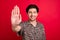 Photo of good mood smiling positive guy showing stop gesture ignore you prohibition isolated on red color background