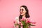 Photo of gorgeous adult girl with long dark hair in round glasses holding amazing bunch of blossom tulips, isolated over pink
