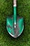 Photo of green shovel with soil on grass