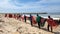 Photo of a group of fishermen walking in a line at the sea shore with a long fish net