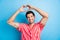 Photo of handsome appreciative man with bristle dressed striped shirt showing heart symbol over head isolated on blue