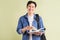 Photo of handsome asian student smiling and holding book in hand