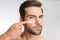 Photo of handsome half-naked man applying facial cream