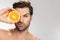 Photo of handsome half-naked man looking at camera and holding orange