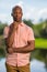 Photo handsome young black man smiling and looking of camera. Hand posed under his chin in an outdoor setting