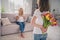 Photo of happy amazed mother and daughter give tulips flowers surprise gift sit sofa indoors inside house