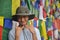 Photo of a happy asian young guy looking at camera with making rock sign with his hands, posing against tibetan buddhist prayer fl