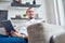 Photo of happy brunet looking to side with tablet in his hands sitting on sofa in room .