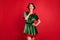 Photo of happy minded dreamy young woman santa helper look empty space idea plan isolated on red color background