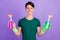 Photo of happy positive cheerful young man hold bottles cleaner housekeeper isolated on purple color background