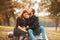 Photo of happy pregnant couple sitting on the banch in park, beautiful forehead kiss