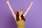 Photo of happy triumphant young woman raise fists good mood winner yes isolated on purple color background