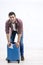 Photo of happy young man ready for the trip with his suitcase packed over white background.