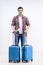 Photo of happy young man ready for the trip with his suitcase packed over white background.