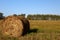 Photo of hay bale in the foreground in rural field