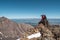 Photo hunting high in the mountains. Photographer with a large backpack sits on the edge of a cliff. Dangerous mountains and abyss