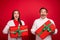 Photo of husband wife happy couple gift christmas look empty space xmas spirit isolated on red color background