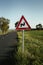 Photo of illuminated and warning road sign - double curve next to the road on meadow. Double Bend warning road sign on country